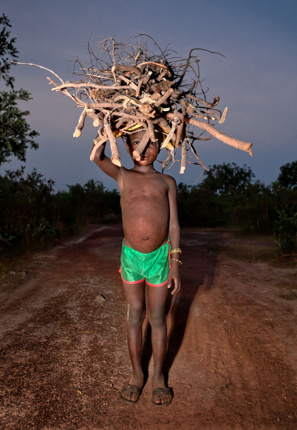 As pessoas que cruzam uma estradinha de uma vila rural africana 01