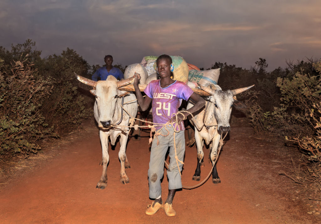 As pessoas que cruzam uma estradinha de uma vila rural africana 03