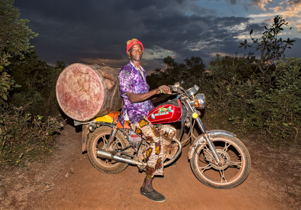 As pessoas que cruzam uma estradinha de uma vila rural africana 04