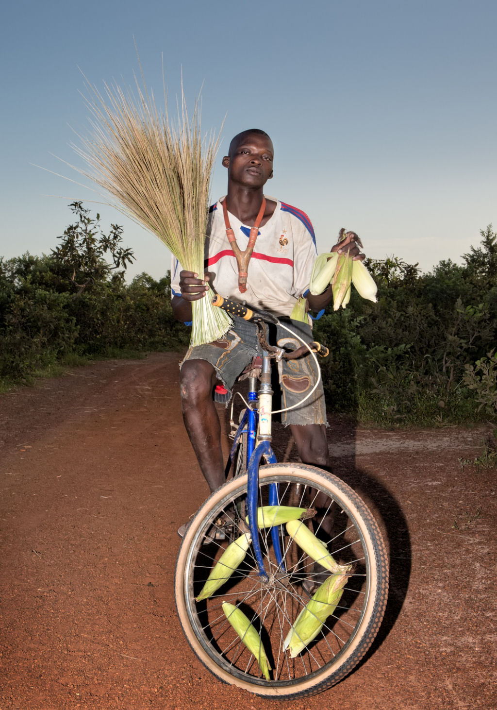 As pessoas que cruzam uma estradinha de uma vila rural africana 05