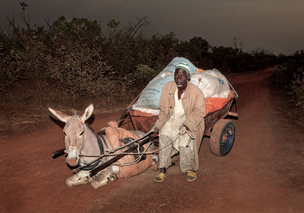 As pessoas que cruzam uma estradinha de uma vila rural africana 12