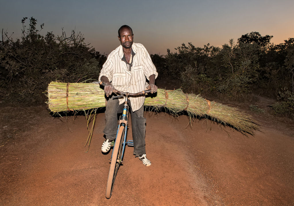 As pessoas que cruzam uma estradinha de uma vila rural africana 13