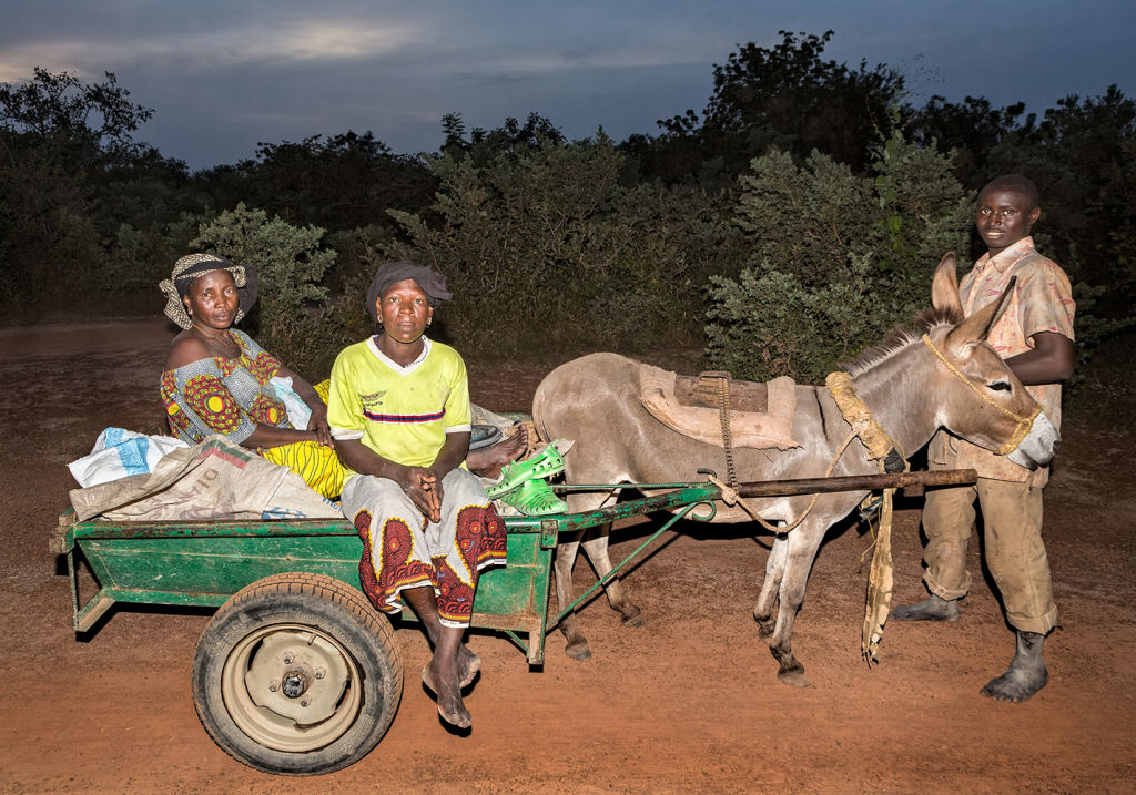 As pessoas que cruzam uma estradinha de uma vila rural africana 15