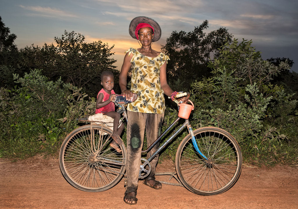 As pessoas que cruzam uma estradinha de uma vila rural africana 16