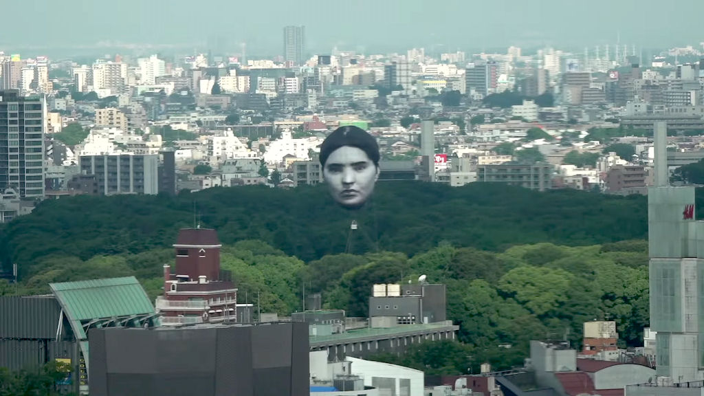 Uma cabeça gigante flutuante aparece no céu acima do centro de Tóquio