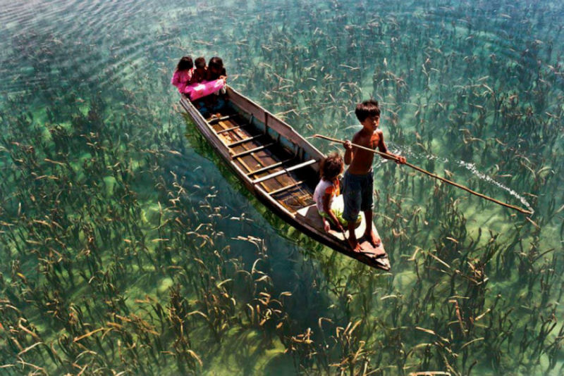 Crianças em um lago de águas cristalinas em Sabah, Malásia.