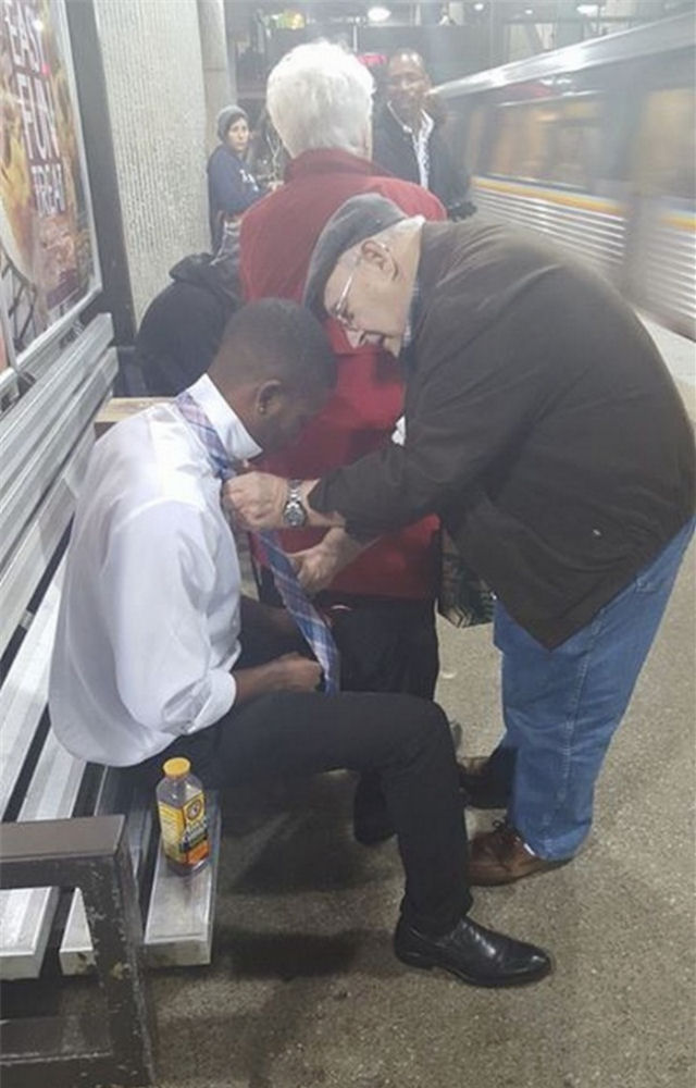 Um senhor ajuda um jovem desconhecido a dar o n na gravata antes da sua primeira entrevista de emprego.