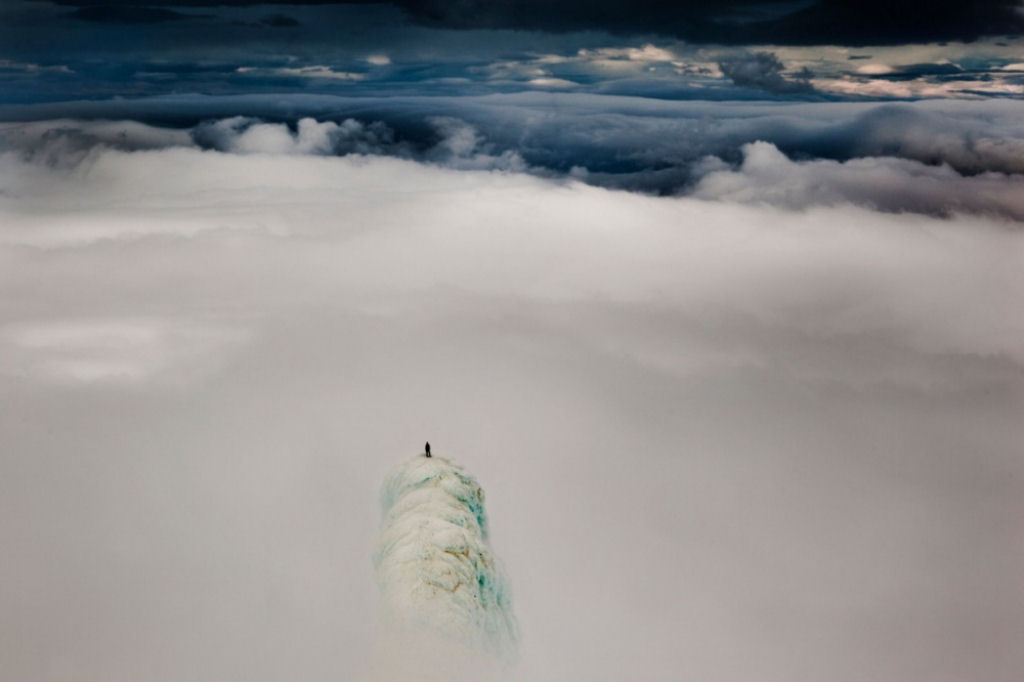 Alpinista no pique de uma montanha na Islndia. Por Will Copestake.