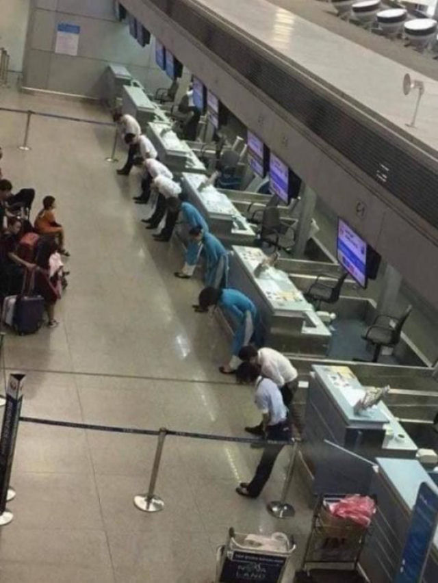 Vôo atrasado no Japão. Os empregados da empresa aérea inclinam-se ante os passageiros para desculpar-se.