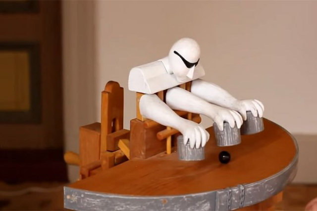 Brinquedo de madeira movido a manivela realiza incrível truque do jogo dos copinhos
