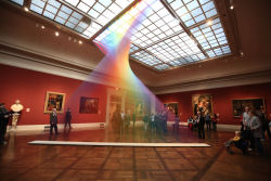 Este arco íris artificial preso em uma galeria de arte foi feito com milhares de fios coloridos