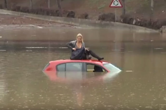Mulher é resgatada da inundação em cima do teto de seu carro