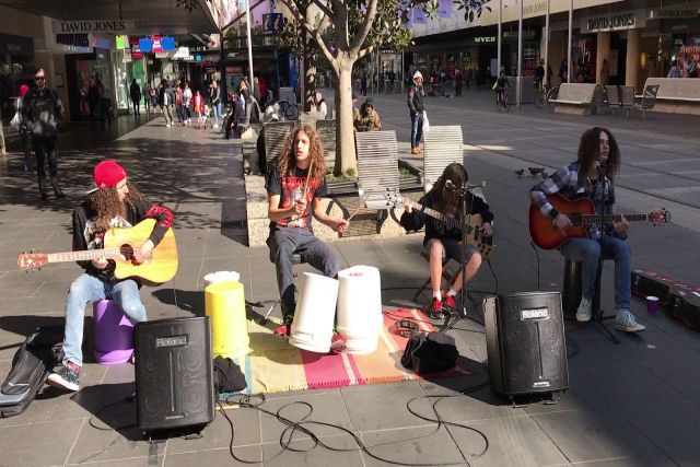 Grupo de adolescentes toca Metallica na frente de um centro comercial