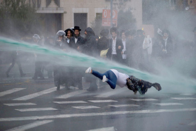 Transeunte recebe rajada de canhão de água durante um protesto em Israel