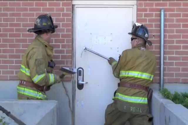 Dois bombeiros demonstram como abrir  fora uma porta de alta segurana em pouco mais de 1 minuto