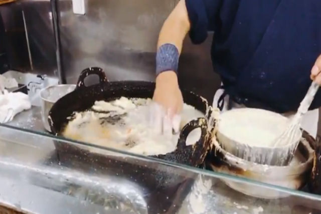 Chef japons cozinha enfiando os dedos em azeite fervendo sem queimar-se