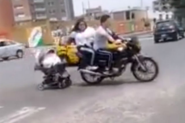 Um casal de moto reboca um carrinho de beb pelas ruas do Peru