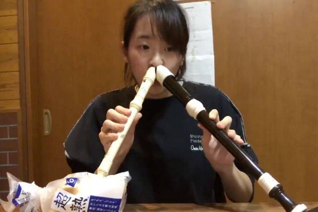 Japonesa com talento nico toca simultaneamente duas melodias separadas em duas flautas usando o nariz