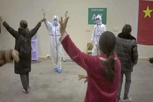 Pessoal médico de um hospital em Wuhan com trajes de proteção dança com pacientes do Covid-19 para animá-los