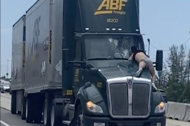 Homem viaja sobre capô de caminhão em uma estrada na Flórida, em uma cena própria de cinema de ação<br />
