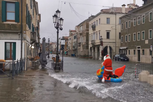 Papai Noel com máscara navega em uma boia pelas ruas inundadas de Veneza