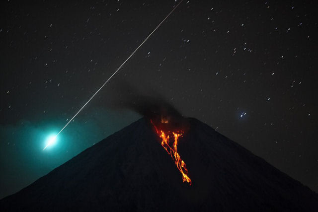 Timing perfeito: clique fortuito enquadra um meteoro sobre um vulcão entrando em erupção
