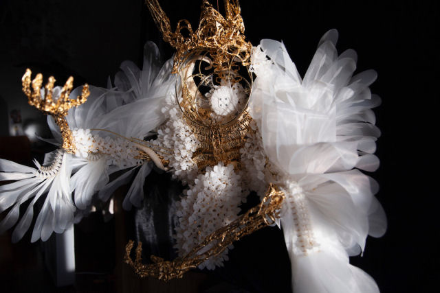 Flores delicadas e asas flutuam sobre esqueletos dourados em bela esculturas cinticas
